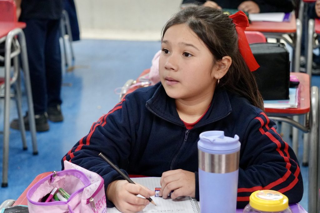 Estudiante escribiendo en su cuaderno durante la clase