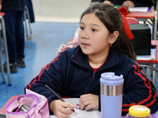Estudiante escribiendo en su cuaderno durante la clase