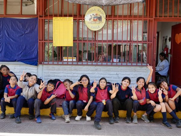 Estudiantes sentados frente al acceso principal de la escuela